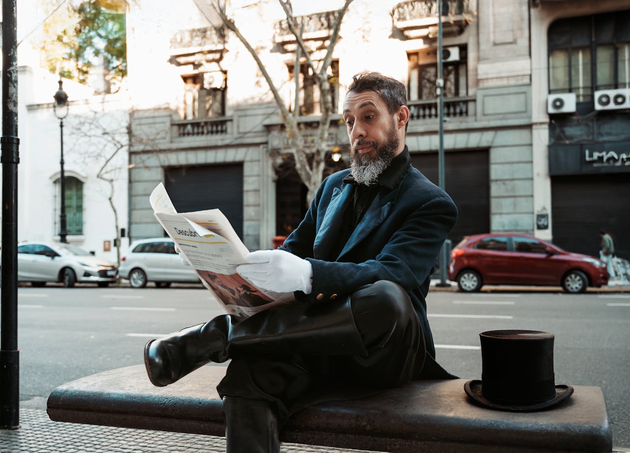 An adult man in formal attire reads a newspaper on a bench in Buenos Aires, Argentina.